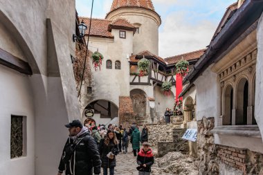 Group of people are walking down a narrow street, castle of Dracula. December 16, 2024 Bran Romania. clipart