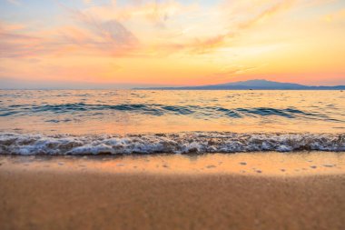 Okyanus sakin ve gökyüzü güzel turuncu bir renktir. Güneş batıyor, sıcak ve huzurlu bir atmosfer yaratıyor.