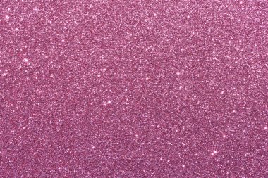 Pembe bir arka plan ve parlak bir doku. Arka plan pembe ve simler de pembe. Işıltı arka fonun her tarafına saçılmış. Parlak ve parlak bir görüntü veriyor.