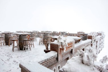 Kışın harikalar diyarında boş masaları ve sandalyeleri olan karla kaplı bir kafeterya..
