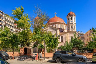 Çan kulesi ve yeşil çatısı olan bir kilise. Çan kulesi kırmızı ve beyaz. Kilise ağaçlarla çevrilidir. 8 Ağustos 2024 Selanik Yunanistan