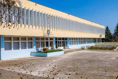 Güneşli bir günde modern sarı ve mavi binalı boş bir okul bahçesi. 2 Mayıs 2023 Romanesti Moldova.