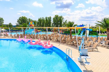 Pembe şamandıralı bir havuz ve şezlonglu plaj alanı. Manzara eğlenceli ve rahatlatıcı. 8 Haziran 2024 Balti Moldova