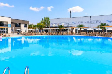 Arka planda mavi suyu ve beyaz binası olan büyük bir havuz. Havuz sandalyeler ve şemsiyelerle çevrilidir. 8 Haziran 2024 Balti Moldova