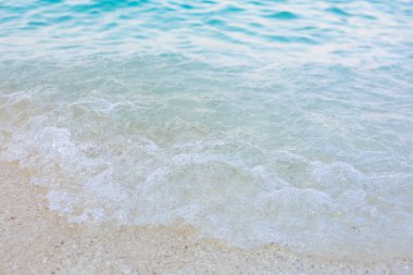 Okyanus sakin ve su berrak. Dalgalar küçük ve naziktir. Kumsal kumlu ve su güzel mavi bir renk.