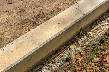 Üzerinde bir sürü çamur ve yaprak olan beton bir kaldırım. Toprak kahverengi ve yapraklar yeşil.