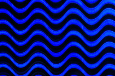 Görüntü mavi ve siyah bir dalga deseni. Mavi ve siyah renkler derinlik ve hareket hissi yaratırken dalgalı çizgiler sahneye dinamik ve enerjik bir his katıyor.