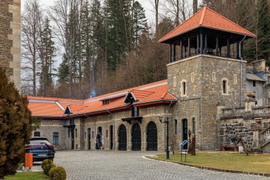 Kırmızı çatılı ve büyük kulesi olan bir bina. 15 Aralık 2024 Busteni Romanya.