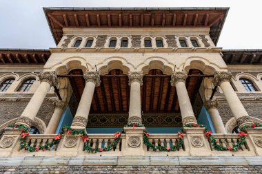 Balkonlu binanın üzerinde kırmızı ve yeşil çelenk var. 15 Aralık 2024 Busteni Romanya.