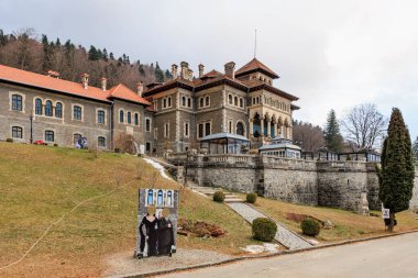 Geniş bina, çimlerin üzerinde bir tabela, Cantacuzino Kalesi. 15 Aralık 2024 Busteni Romanya.