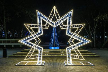Şehir parkında geceleyin aydınlatılmış yıldız heykeli. 27 Aralık 2024 Balti Moldova.