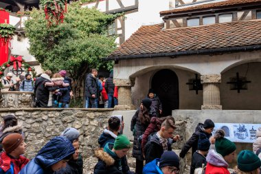 Group of people are standing outside a building, castle of Dracula. December 16, 2024 Bran Romania. clipart