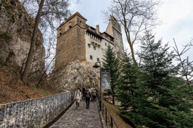 Bir grup insan Drakula şatosunun önünde bir patikada yürüyor. 16 Aralık 2024 Bran Romanya.