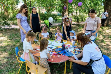 Bir grup çocuk bir tablo çizimi ve boyama etrafında oturuyorlar. Sahne eğlenceli ve eğlenceli. 1 Haziran 2024 Balti Moldova.