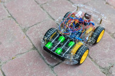 Önünde yeşil ışık olan robot araba. Bir tuğla kaldırımda. Robot araba plastikten yapılmış ve bir bataryası var. 1 Haziran 2024 Balti Moldova.