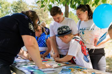 Bir grup insan bir masanın etrafında toplanmış oyun oynuyorlar. Bir kadın balon tutuyor. 1 Haziran 2024 Balti Moldova.