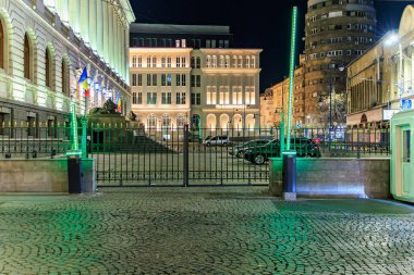 Aydınlatılmış tarihi binanın ve şehir merkezindeki kaldırım taşı sokağının gece manzarası. 8 Mart 2025 Bükreş Romanya.