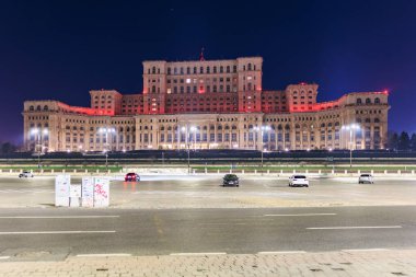 Bükreş 'in parlamento sarayının gece görüşü kırmızı ışıklarla aydınlandı. 8 Mart 2025 Bükreş Romanya.