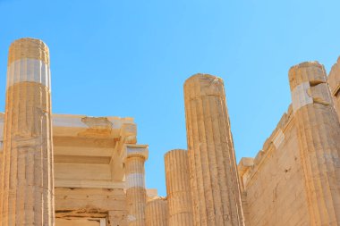 Bir binanın parçası olan uzun, kahverengi sütunlar. Sütunlar sahnenin dört bir yanına dağılmış durumda, bazıları tek başına, diğerleri ise Atina 'daki Akropolis kentinde bir araya gelmiş durumda.