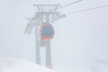 Kış boyunca karlı dağ sisinde kırmızı teleferik..