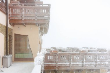 Sisli bir kış sahnesinde kırsal ahşap bir dağ evinin karla kaplı balkonunda..