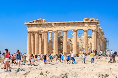 Büyük bir grup insan büyük bir binada sütunlarla yürüyorlar. İnsanlar dağıldı ve bazıları sırt çantası taşıyor. Manzara hareketli ve hareketli. 9 Ağustos 2024 Atina Yunanistan