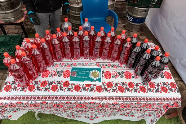 Açık hava pazarında kırmızı ve siyah şişelerin çiçek masa örtüsü üzerinde toplu şarap görüntüsü. 15 Şubat 2024 Balti, Moldova.