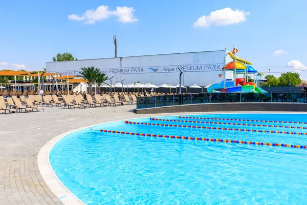 Kaydıraklı bir havuz ve arka planda bir bina. Havuz sandalyeler ve şemsiyelerle çevrilidir. 8 Haziran 2024 Balti Moldova