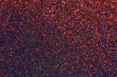 Kırmızı ve mavi ışıltılı bir arka plan. Arka plan pek çok küçük parıltı parçasından oluşur.