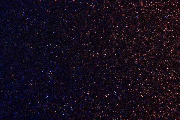 Koyu mavi ve kırmızı bir arka plan ve bir sürü parıltı. Parıltı tüm arka plana yayılmış ve yıldızlı bir gece gibi görünüyor.