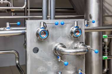 Paslanmaz çelik sanayi valfleri ve modern bir üretim tesisinde mavi saplı borular..