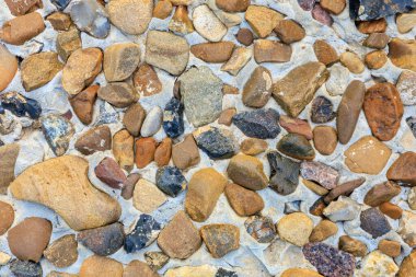 Kum ve kayadan yapılmış bir duvar. Duvar birçok farklı boyutta kayalardan yapılmıştır. Duvar kahverengi ve bronzlaşmış.