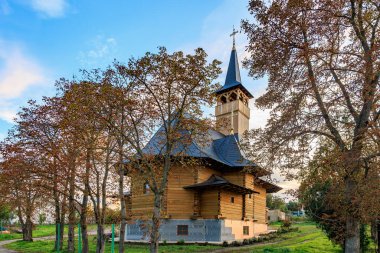 Kırsal alanda günbatımında sonbahar ağaçlarıyla çevrili kırsal ahşap kilise..