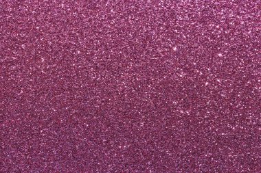Pembe parlak bir yüzeye yakın çekim. Yüzey, yüzeyin her tarafına saçılmış küçük parıltı parçalarından oluşur. Parıltı çeşitli boyut ve renklerde.