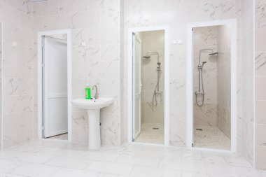 Mermer kiremitler ve beyaz eşyalar ile modern umumi duş odası. 17 Temmuz 2024 Balti Moldova.