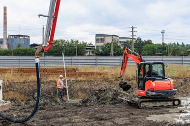 İnşaat alanı kazıcı ve beton pompa kullanan işçiler. 25 Haziran 2024 Balti Moldova