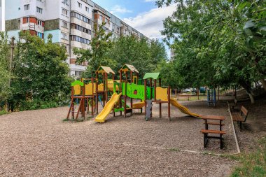 Çevresi ağaçlar ve apartmanlarla çevrili şehir parkındaki renkli çocuk parkı. 30 Haziran 2024 Balti Moldova.