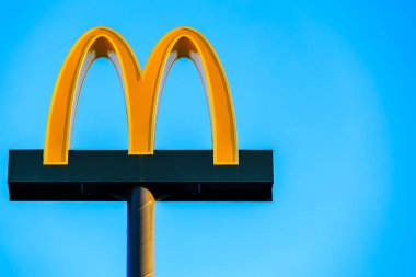 McDonald 's tabelası mavi gökyüzünün önündeki bir direkte, sağdaki telif boşluğunda. 21 Ekim 2024 Balti Moldova.