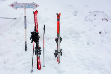 Kıpkırmızı kayaklar ve karlı dağ arazilerinde yön işaretleri olan kutuplar. 15 Aralık 2024 'te Romanya.