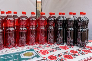 Açık hava pazarında desenli masa örtüsünün üzerinde renkli şarap şişeleri. 15 Şubat 2024 Balti, Moldova.