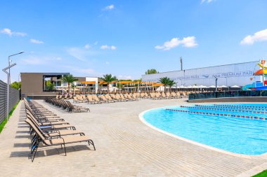 Bir sürü şezlonga ve şemsiyeye sahip bir havuz. Havuz bir çitle çevrili. 8 Haziran 2024 Balti Moldova