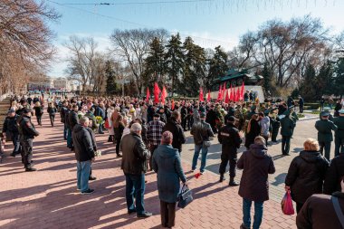 Dışarıda, çeşitli kalabalık ve kırmızı bayraklı tarihi anıtın yanında toplanıyorlar. 26 Mart 2024 Balti, Moldova.