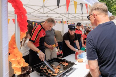 Alman gönüllüler 19 Mayıs 2024 'te Balti Moldova' da Avrupa Günü 'nde ızgara sosis pişiriyor ve otantik Alman mutfağını ziyaretçilerle paylaşıyor.