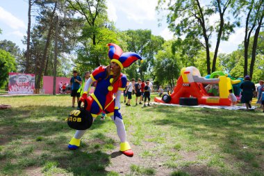 Renkli soytarı parktaki açık hava festivalinde kalabalığı eğlendiriyor. 31 Mayıs 2024 Balti Moldova.