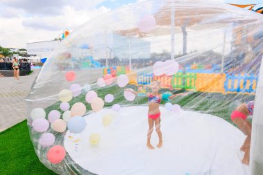 Bir kız açık bir balonda balonlarla oynuyor. Balon farklı renk ve boyutlarda balonlarla dolu. Sahne canlı ve eğlenceli. 8 Haziran 2024 Balti Moldova