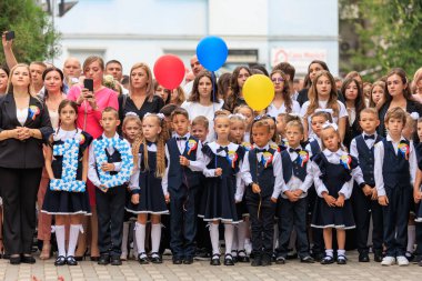 Okul etkinliğindeki çocuklar ve yetişkinler balonlar ve numara işaretleriyle. 2 Eylül 2024 Balti Moldova.