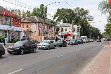 Dükkanların yakınına dizilmiş arabalarla kalabalık bir sokak manzarası. 11 Eylül 2024 Balti Moldova.