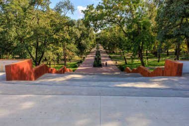 Çeşmeye çıkan taş merdivenli bir park. Basamaklar kırmızı ve çeşme parkın ortasında. 25 Eylül 2024 Balti Moldova