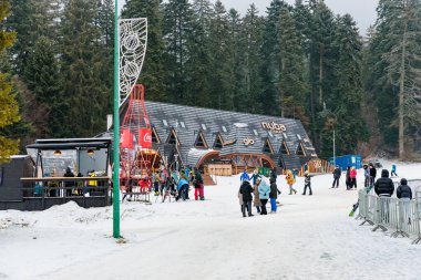 Karlı dağ kulübesi ve kış harikalar diyarında ziyaretçiler. 15 Aralık 2024 'te Romanya.