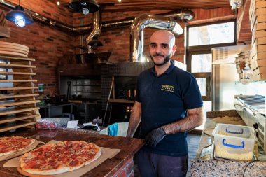 Kır mutfağında pizza şefi ve tezgahta yeni yapılmış pizzalar. 28 Aralık 2023 Balti Moldova.